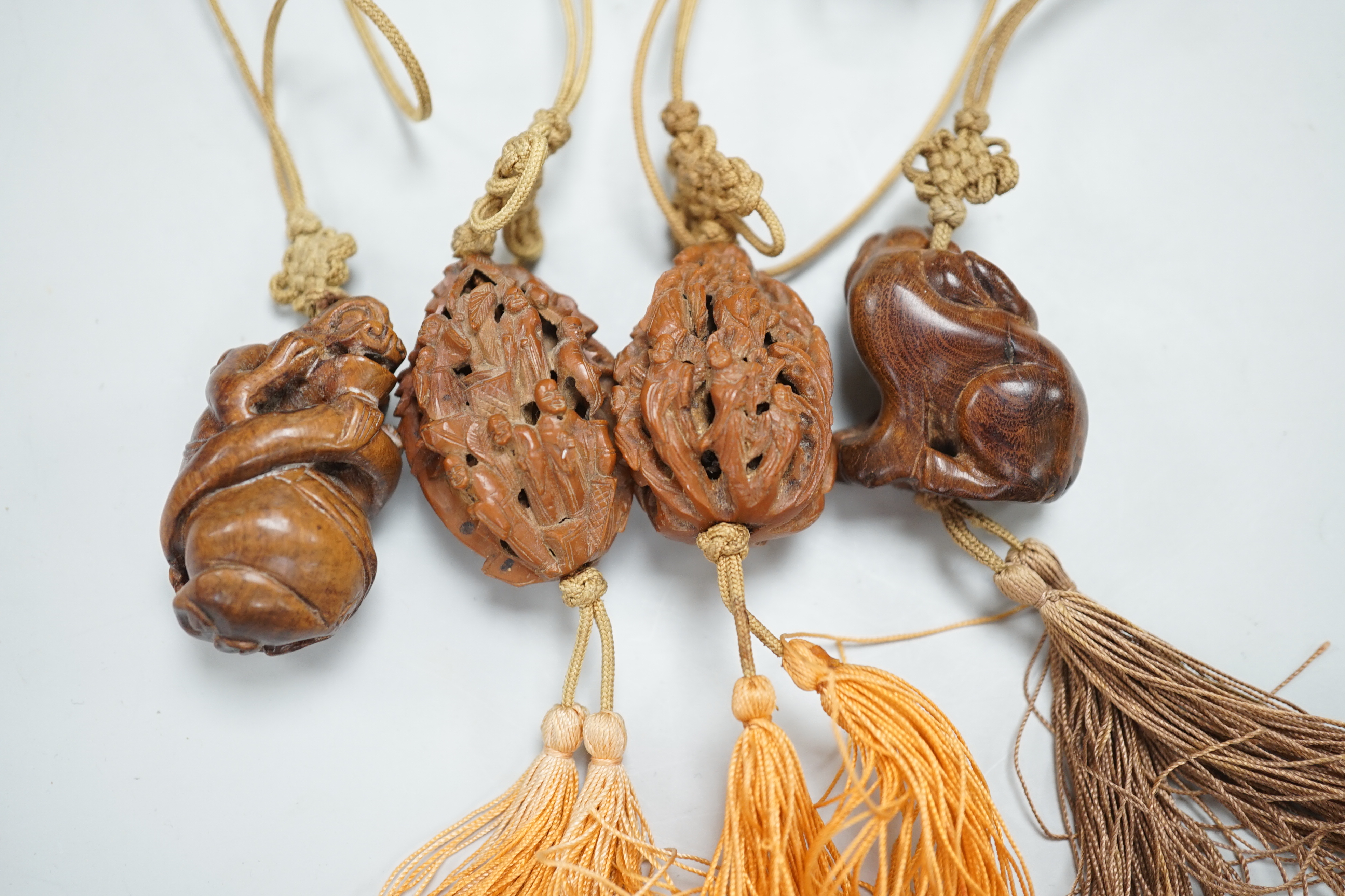 Two Chinese peach stone carvings and two carved wood toggles on a silk cord